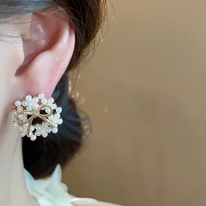 Detailed close-up showing a 14k gold plated bow-knot pearl stud earring worn on the ear
