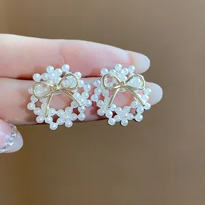 Close-up detail of elegant 14k gold plated bow pearl wreath stud earrings for women