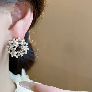 Detailed close-up view of elegant 14k gold-plated bow-knot pearl wreath earring on ear