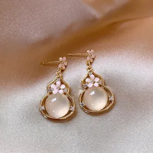 Close-up of elegant gourd-shaped drop earrings with pink flowers and crystals