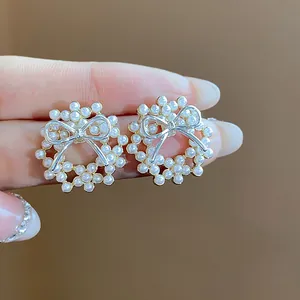 Close-up of elegant pearl wreath earrings with silver bow detail and gold plating