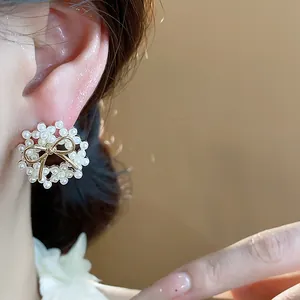 Detail view of an elegant 14k gold plated wreath earring with pearls and a bow.