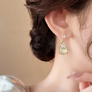 Macro view of a luxurious vintage gourd drop earring with delicate white floral detail