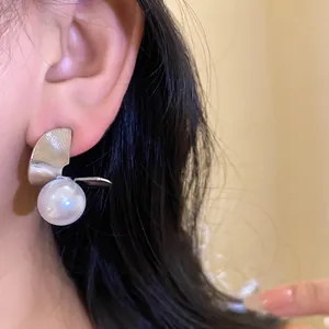Gros plan détaillé montrant une boucle d'oreille élégante en métal torsadé et perle