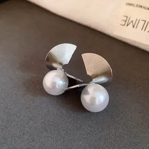 Vue détaillée des boucles d'oreilles en éventail en métal argenté avec perles blanches.