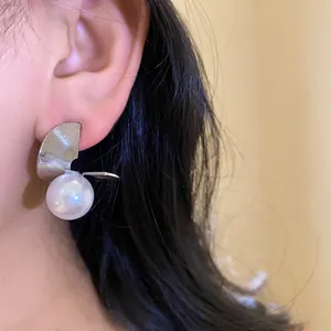 Vue détaillée de la boucle d'oreille en métal torsadé argenté et perle sur un modèle