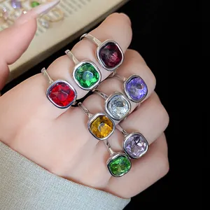 Close-up of vibrant vintage square crystal open rings in various colors worn on hand
