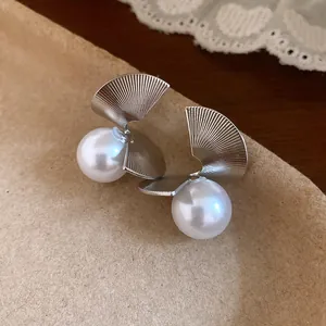 Gros plan détaillé de boucles d'oreilles en éventail torsadées avec perles et texture linéaire