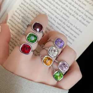 Close-up detail of multiple vintage square colorful gemstone open rings worn on a hand