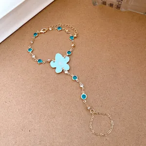 Detailed close-up of a gold hand harness featuring a blue resin flower and rhinestones.