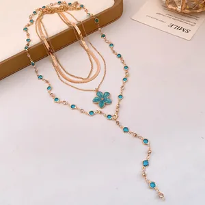 Vista ravvicinata degli strati intricati e del ciondolo a fiore blu di questa collana