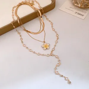 Dettaglio ravvicinato di una collana d'oro a più strati con ciondolo a fiore in smalto giallo