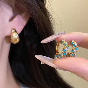 Close-up detail of vintage gold hoop earrings with blue turquoise and clear crystals