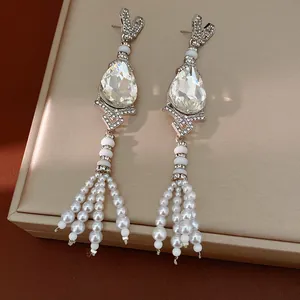 Macro detail of vintage teardrop earrings featuring crystal stones and pearl tassels
