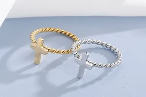 Close-up of twisted rope stainless steel rings with cross charms in gold and silver