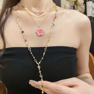 Dettaglio collana dorata multistrato con ciondolo a fiore rosa e pietre colorate