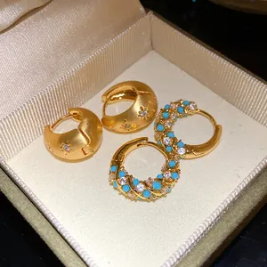Detailed view of vintage gold hoop earrings with turquoise and white crystals in box.