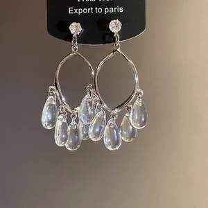 Silver needle earrings with clear resin water drop tassels in French light luxury style.
