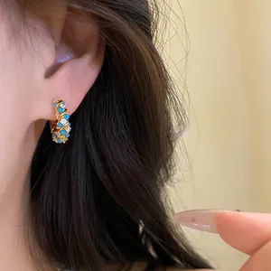 Macro detail of French retro style gold hoop earrings with blue turquoise and crystals
