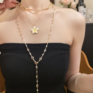 Dettaglio della collana dorata a più strati con pendente a fiore e accenti di cristallo.