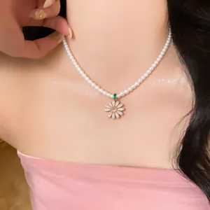 Close-up detail of an elegant pearl necklace with a sparkling zirconia daisy flower pendant.