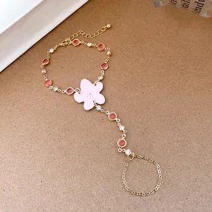 Macro view of gold slave bracelet featuring pink resin flower and red crystals
