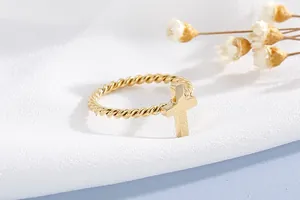 Detail of gold twisted rope ring featuring a polished vertical cross charm