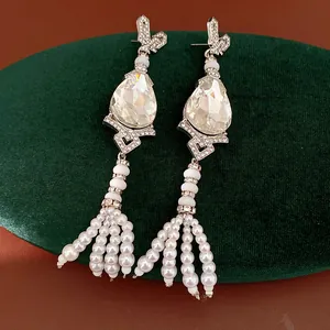 Close-up detail of vintage teardrop earrings with rhinestones and pearl tassels.