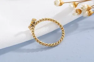 Detailed macro view of gold plated stainless steel twisted rope ring with cross design