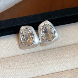Detailed close-up of geometric silver stud earrings with large oval-cut rhinestones