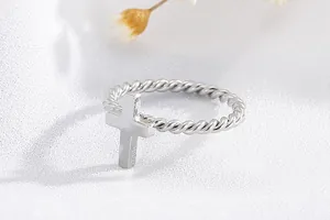 Detailed view of a stainless steel twisted rope ring featuring a polished silver cross charm.