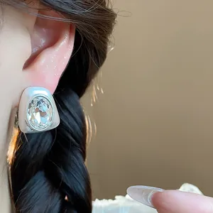 Close-up of silver-tone irregular geometric stud earring with large clear crystal.