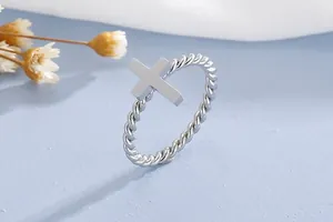 High-quality close-up detail of a stainless steel twisted band ring with a cross design