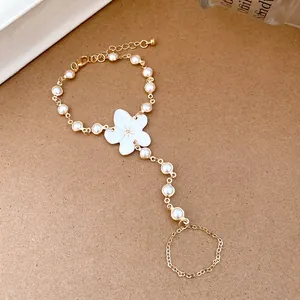 Detail of elegant resin flower finger bracelet with white pearls and gold chain.
