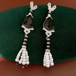 Close-up of vintage teardrop pearl earrings with black stones and tassels