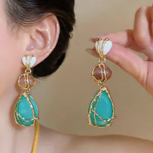 Detalle de pendientes colgantes de tres niveles estilo corte vintage con hilo de oro
