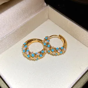 Close-up of vintage gold hoop earrings with turquoise and white stones in a gift box