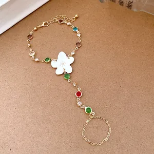 Detailed view of a gold-plated slave bracelet featuring a white resin flower and colorful crystals.
