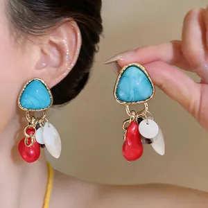 Primer plano detallado de pendientes geométricos vintage con colgantes de caracol.