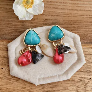 Detalle de pendientes colgantes de estilo corte vintage con turquesa y perlas rojas