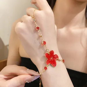 Detail shot of elegant red flower hand chain with gold finish and rhinestones