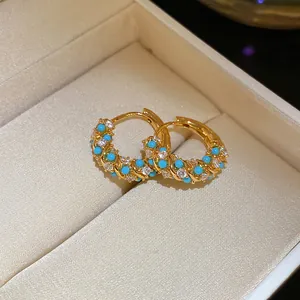 Detailed macro view of French retro gold hoop earrings with turquoise and white crystal stones