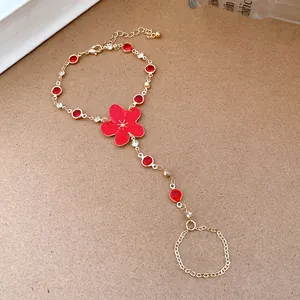 Detail of a red flower finger bracelet with gold chain and sparkling rhinestones