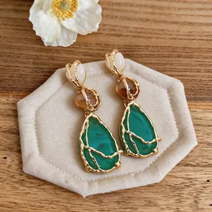 Vista detallada de pendientes vintage de estilo corte con colgantes verde esmeralda.