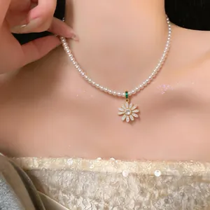 Detail view of shimmering zircon daisy pendant on a classic white pearl necklace