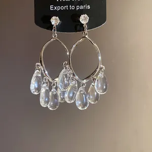 Detail of elegant silver resin teardrop tassel earrings with French luxury style aesthetic.