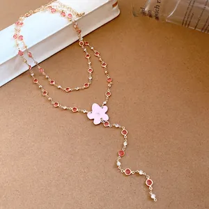Close-up of a double-layered gold necklace with pink resin stones and a flower pendant