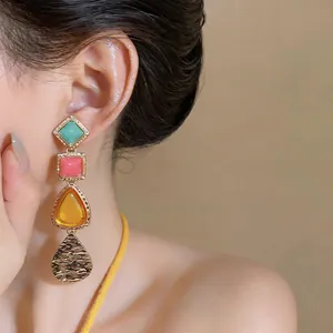 Elegantes pendientes vintage geométricos con piedras de colores en una modelo asiática