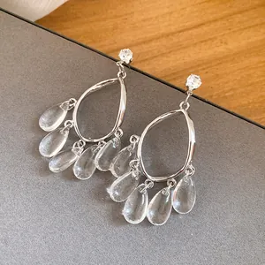 Close-up detail of elegant silver-toned drop earrings with clear resin teardrop tassels
