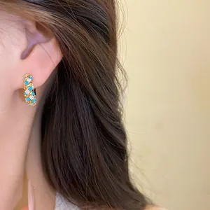 Vintage gold-tone hoop earrings with turquoise and clear crystals on model